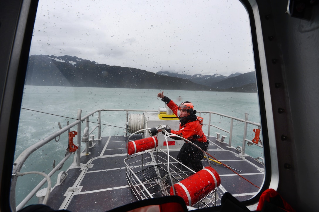 A Coast Guard member signals the aircrew of an MH-60 Jayhawk after securing the hoist basket aboard the 45-foot response boat during training in Port Valdez, Alaska, Sept. 14, 2016. Coast Guard photo by Petty Officer 1st Class Bill Colclough