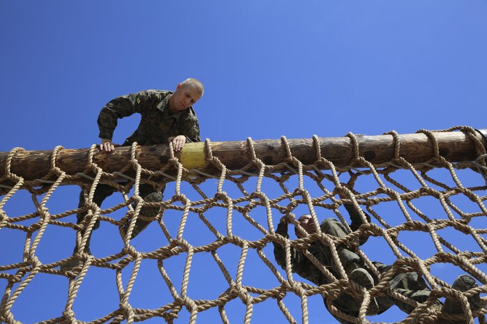 A recruit from Hotel Company, 2nd Recruit Training Battalion, climbs over a cargo net obstacle during Confidence Course II at Marine Corps Recruit Depot San Diego, Sept. 13. Recruits are instructed to climb to the top of the obstacle and maintain a low profile while climbing over. Annually, more than 17,000 males recruited from the Western Recruiting Region are trained at MCRD San Diego. Hotel Company is scheduled to graduate Nov. 9.