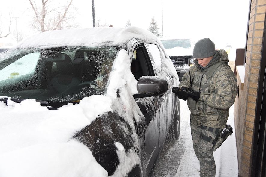 A security forces Airman checks IDs at the main gate Jan. 6, 2015, at Malmstrom Air Force Base, Mont. Individuals are encouraged to prepare their vehicles for winter before it snows, including changing washer fluid. (U.S. Air Force photo/Airman Collin Schmidt)