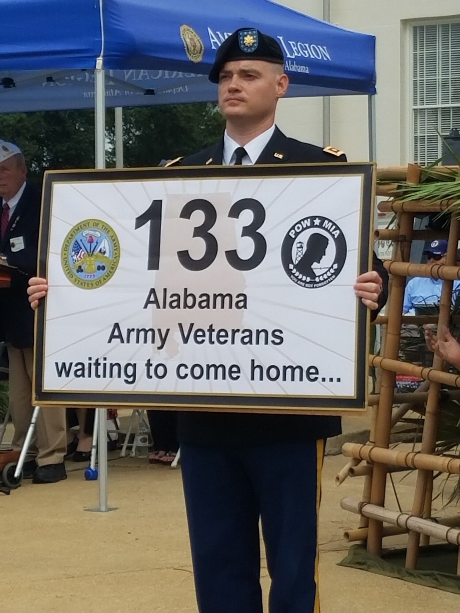 Army Maj. Travis Bassett, Air Command and Staff College student, holds a sign indicating the number of Alabamians from the Army who are still in MIA status. During the ceremony, Brooks Barrow, Marine Corps league, escorted the American flag to each service representative while their service song played. (U.S. Air Force photo/Eric Sharman)
