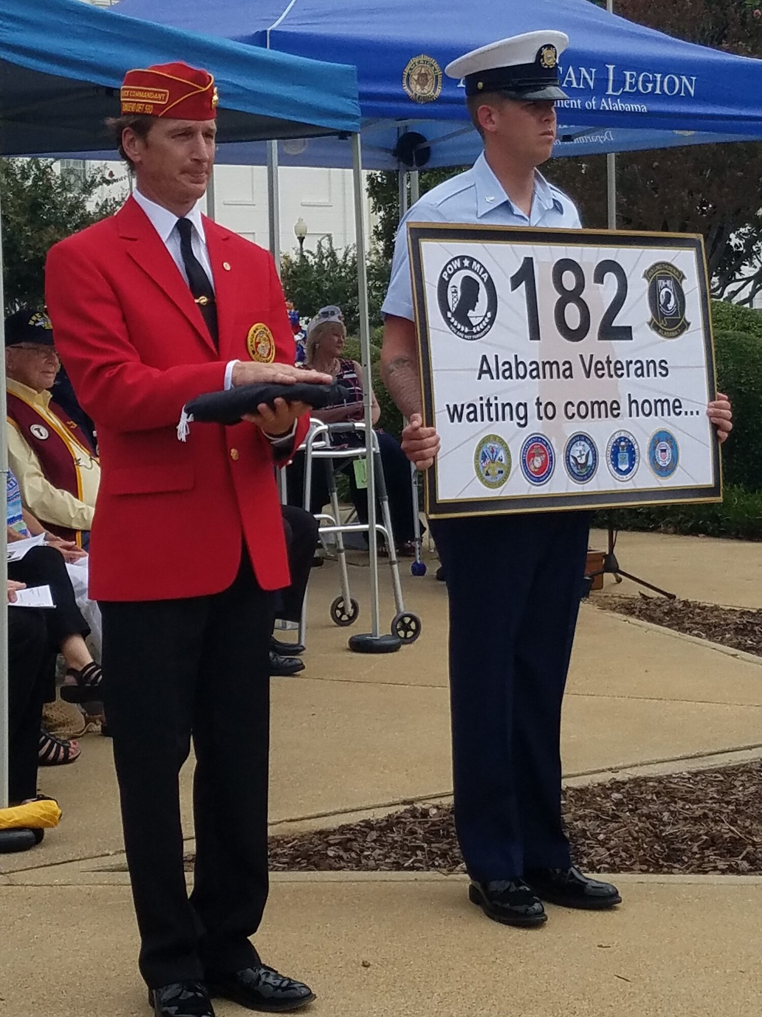 Coast Guardsmen, Petty Officer Third Class Dalton Lynch, holds a sign indicating the number of Alabamians from the Coast Guard who are still in MIA status. During the ceremony, Brooks Barrow, Marine Corps league, escorted the American flag to each service representative while their service song played. (U.S. Air Force photo/Eric Sharman)