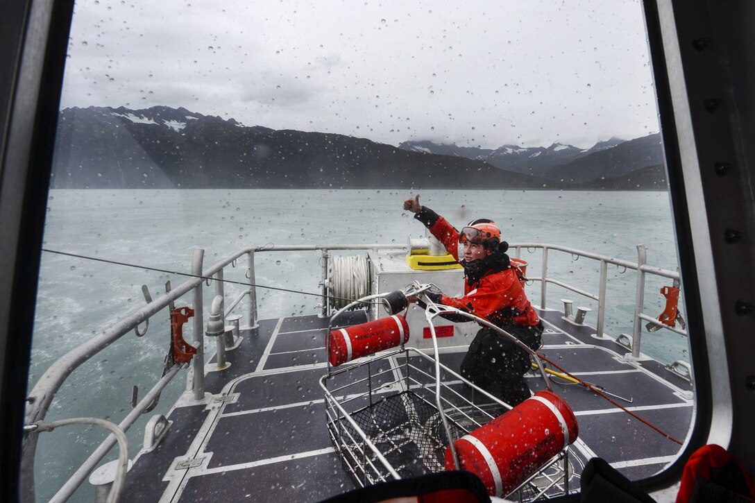 A Coast Guard member signals to the aircrew of an MH-60 Jayhawk that he has secured the hoist basket onboard the 45-foot response boat during rescue training in Port Valdez, Alaska, Sept. 14, 2016. Coast Guard photo by Petty Officer 1st Class Bill Colclough