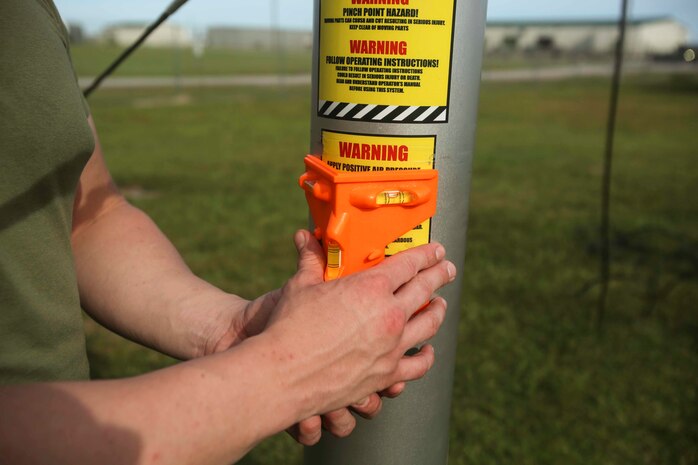 A Marine uses a leveling device to ensure a Meteorological Radar Subsystem is even with the ground at Marine Corps Air Station New River, N.C., Sept. 14, 2016.  The MRS, being leveled by Marines with Meteorology and Oceanography platoon, 2nd Intelligence Battalion and Marine Air Traffic Control Detachment Bravo, Marine Air Traffic Control Squadron 2, is used by forecasters to predict tropical storms and better understand cloud cover. (U.S. Marine Corps photo by Lance Cpl. Ashley Lawson/Released)
