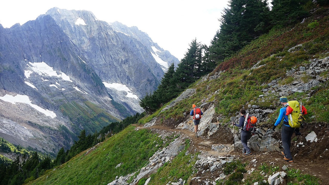 Ben Stilin (front), Melanie Stam (middle) and Capt. Nick Anthony (rear) hike down a switchback on their way to Cascade Pass in North Cascades National Park, Washington, Sept. 10, 2016. After encountering an exhausted 77-year-old Norman Petty on a hike with his wife Barbara, photographer Colin Ayers, the pictured climbers and Catherine Mitchell (not pictured) led the couple visiting from Dunwoody, Georgia, to safety by transporting Norman Petty more than three miles using an impromptu support system. Anthony, from Norman, Oklahoma, is a U.S. Marine Corps recruiting management officer based in Seattle. Ayers, from Spokane, Washington, is a University of Washington chemical engineering student. Mitchell, from Seattle, is a content project manager at Microsoft. Stam, from Atlanta, is a Microsoft data analyst. Stilin, from Seattle, is a ski instructor at Husky Winter Sports.