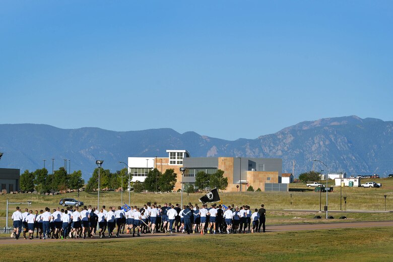 Schriever Airmen run with the POW/MIA flag in group formation during the prisoners of war and missing in action run at Schriever Air Force Base, Colorado, Thursday, Sept.15, 2016. Many squadrons ran around the base at the run’s start before handing the flag off to individual units who kept it moving for 24-hours straight.  (U.S. Air Force photo/Dennis Rogers)