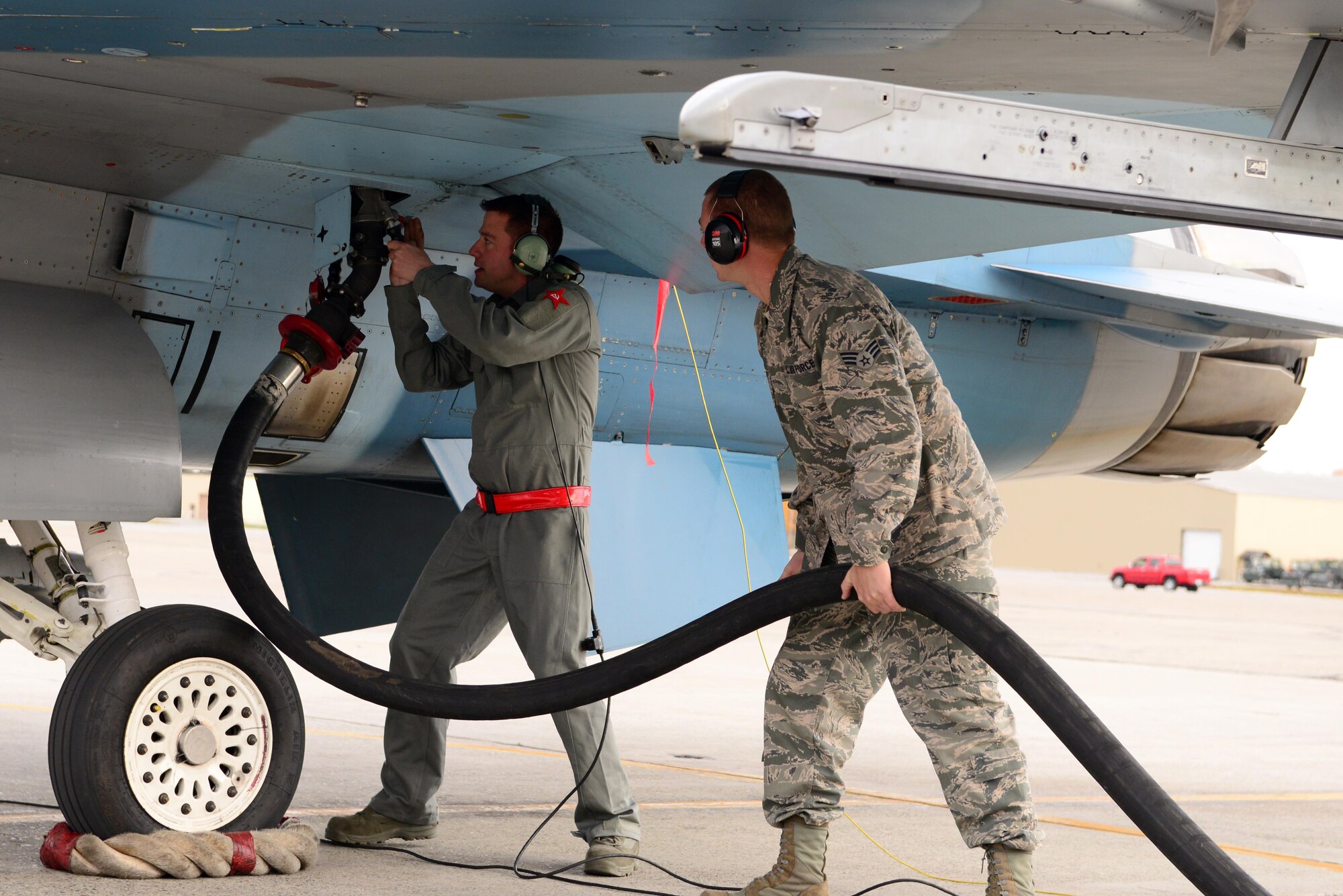 U.S. Air Force Senior Airman Jason Watson, a 354th Aircraft Maintenance Squadron crew chief, and Senior Airman Jacob Goetz, a 354th Logistics Readiness Squadron fuels distribution operator, lift a fuel pump into place on an F-16 Fighting Falcon aircraft assigned to the 18th Aggressor Squadron, Sept. 20, 2016, at Eielson Air Force Base, Alaska. Watson and Goetz were responsible for refueling two F-16s during hot pits training. (U.S. Air Force photo by Airman 1st Class Cassandra Whitman)