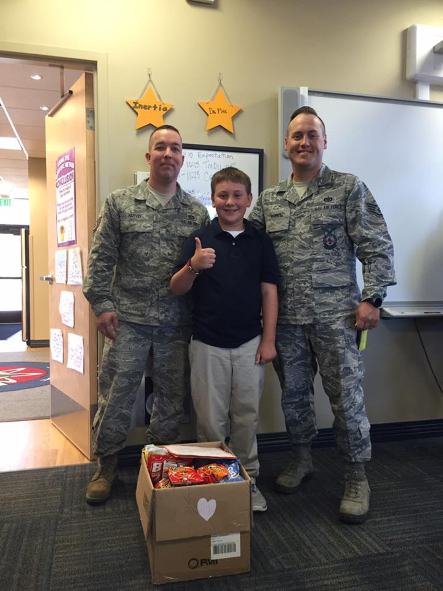 PETERSON AIR FORCE BASE, Colo. – Staff Sgts. Charles Harvey and Derrick Grinnell, 21st Civil Engineer Squadron Fire Emergency Services, accept a box of snacks from a McAuliffe Elementary student at Peterson Air Force Base, Colo., Sept. 16, 2016. The students recently learned about the events of 9/11 and were motivated to collect boxes of snacks to share with first responders at the installation. (Courtesy Photo)