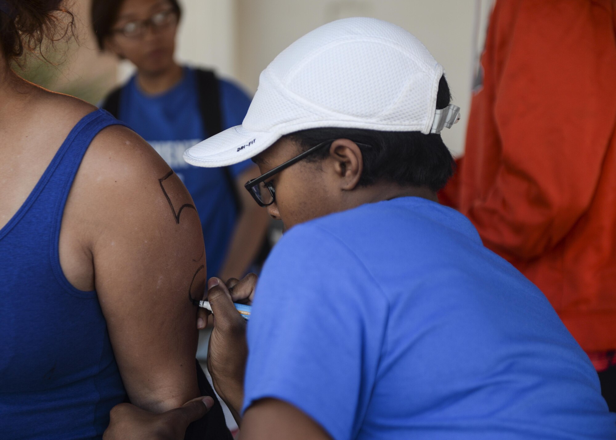 Airman 1st Class Dayna, a fitness specialist with the 49th Force Support Squadron, marks an athlete’s arm before Holloman’s eighth annual Monster Triathlon at Holloman Air Force Base, N.M. on Sept. 17, 2016. Holloman’s Monster Triathlon is hosted by the Domenici Fitness & Sports Center and the 49th Force Support Squadron. (Last names are being withheld due to operational requirements. U.S. Air Force photo by Airman 1st Class Alexis P. Docherty)