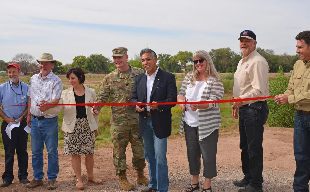 ALBUQUERQUE, N.M. – AMAFCA engineer Nolan Bennet (far right) holds the ribbon that (l-r): AMAFCA director Bruce Thomson; MRGCD director John Kelly; Rio Grande High School principal Amanda De Bell; Albuquerque District Commander Lt. Col. James Booth; Bernalillo County Commissioner Art De la Cruz; AMAFCA director Debbie Stover; and MRGCD chief engineer Mike Hamman prepare to cut, officially opening Pond 187, Sept. 20, 2016.