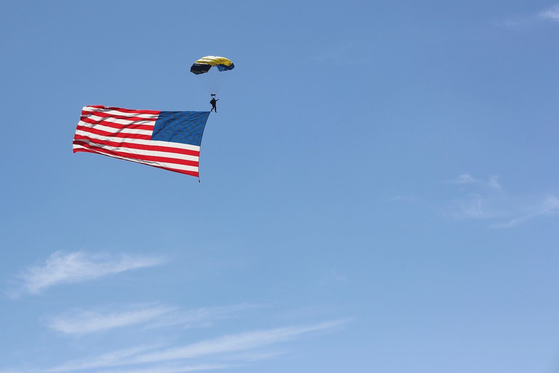 A member of the U.S. Navy Leap Frogs parachute team descends while an American flag trails behind him during the opening ceremony of the 2016 MCAS Miramar Air Show aboard Marine Corps Air Station Miramar, Calif., Sept. 23. After the morning performances, the air show officially kicked-off with an opening ceremony followed by the Marine Air-Ground Task Force demonstration. The MCAS Miramar Air Show showcases world-class performers, military flight demonstration teams, the capabilities of the Marine Air-Ground Task Force and celebrates Miramar’s longstanding relationship with the local San Diego community. (U.S. Marine Corps photo by Cpl. Kimberlyn AdamsReleased)