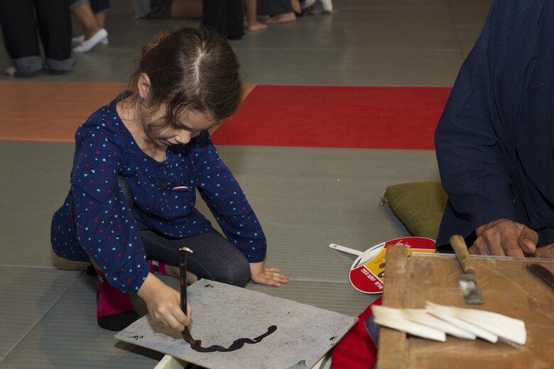 Joannabella Smith, a Marine Corps Air Station Iwakuni resident, practices her calligraphy at the Kumano Brush Festival in Kumano, Japan, Sept. 22, 2016. Air station residents traveled to Kumano with the Cultural Adaptation Program for the Kumano Brush Festival, where they were given an opportunity to participate in a calligraphy competition with the Japanese locals. After attending the festival the residents visited the Fudenosato Kobo Museum where they learned how calligraphy equipment is made. (U.S. Marine Corps photo by Lance Cpl. Joseph Abrego)