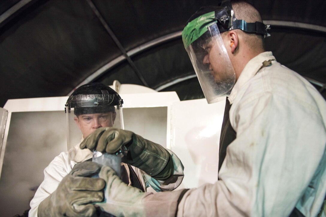 Air Force Tech. Sgt. Corey Briggs, right, and Staff Sgt. Nathan Knight handle a sample of liquid oxygen at Bagram Airfield, Afghanistan, Sept. 14, 2016. Briggs, a cryogenics technician, and Knight, a cryogenics supervisor, are assigned to the 455th Expeditionary Logistics Readiness Squadron. Air Force photo by Senior Airman Justyn M. Freeman