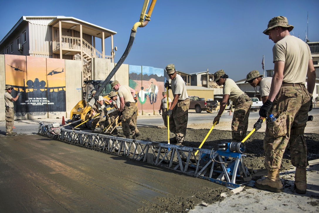 Airmen level concrete using an aluminum screed, a tool used to smooth and flatten concrete, at Bagram Airfield, Afghanistan, Sept. 19, 2016. The airmen are assigned to the 455th Expeditionary Civil Engineer Squadron. Air Force photo by Senior Airman Justyn M. Freeman