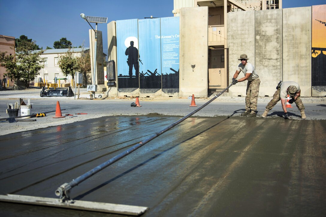 Air Force Staff Sgt. Casey Epps, left, removes imperfections on the surface of wet concrete at Bagram Airfield, Afghanistan, Sept. 19, 2016. Epps is a pavements and equipment specialist assigned to the 455th Expeditionary Civil Engineer Squadron. Air Force photo by Senior Airman Justyn M. Freeman