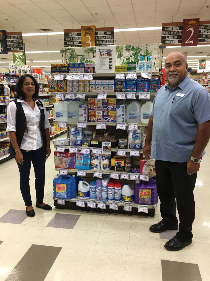 MCAS Yuma Installation Emergency Manager (right) stands in front of a display in the Commissary. The display highlights items needed for an emergency kit. Courtesy photo by MCAS Yuma