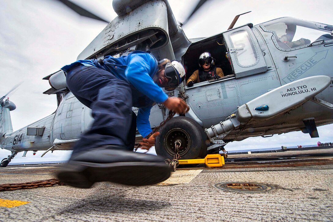 Navy Petty Officer 3rd Class Demetrice Cox secures an MH-60s Seahawk helicopter with chocks and chains on the flight deck of the guided-missile cruiser USS Chancellorsville during Valiant Shield 2016 in the Philippine Sea, Sept. 22, 2016. The biennial exercise focuses on integrating joint training among U.S. forces. The Seahawk is assigned to Helicopter Sea Combat Squadron 12. Navy photo by Petty Officer 2nd Class Andrew Schneider