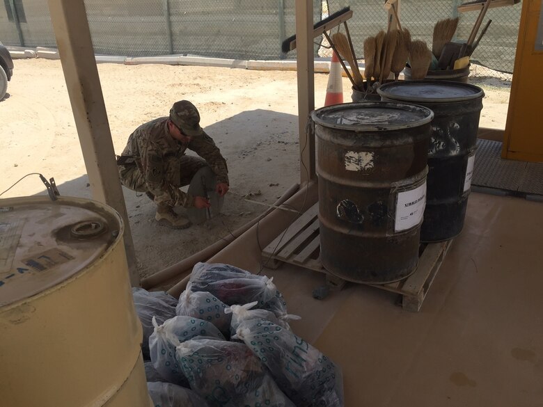 A Soldier inspects a soil sample at a hazardous waste collection point in Camp Arifjan, Kuwait. U.S. forces are readily deployable to anywhere on the planet and have the capability to set up operations under very harsh conditions to meet the required objectives. A set of environmental guidelines is followed to minimize initial impact and alternatives that are more protective of human health and the environment are constantly implemented as operations transition from initial deployment into sustainment.