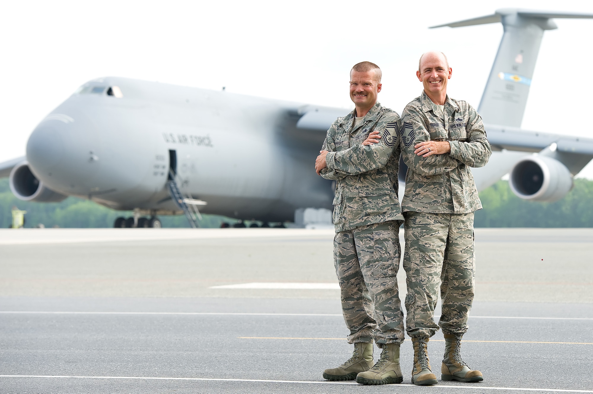 Chief Master Sgts. Robert Wright (left), 436th Maintenance Group, and Bryan Ford, 512th Maintenance Group, stand together July 3, 2013, on the flightline of Dover Air Force Base, Del., where they first began working with each other in 1994, after having known each other through their high school years in Virginia during the mid-1980s. Wright and Ford, an active-duty and reserve Airman, teamed together and led numerous Total Force Initiatives for the Air Force and Air Force Reserve. Since the photo was taken, Wright has retired but still serves on base as a contractor. (U.S. Air Force photo by Roland Balik)