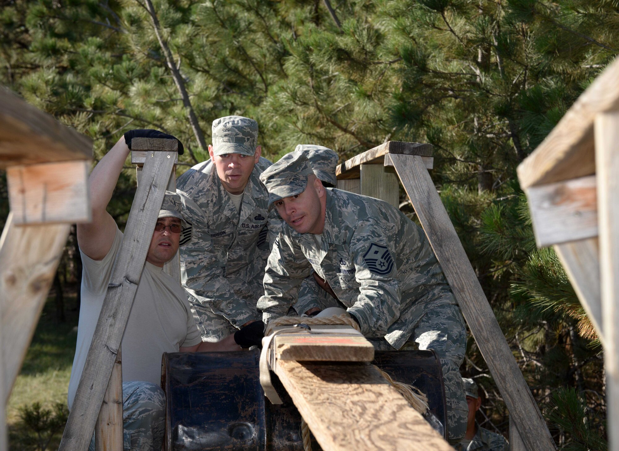 Master Sgt. Paul Lanoue, left, Master Sgt. Christopher Davidson, center, and Master Sgt. Patrick Hill, right, first sergeants at Ellsworth Air Force Base, S.D., assemble a makeshift bridge during the Leadership Reaction Course at the South Dakota National Guard West Camp Rapid training facility, Rapid City, Sept. 15, 2016. Many of the obstacles required swift and creative thinking in order to achieve the given task. (U.S. Air Force photo by Airman 1st Class Donald C. Knechtel)