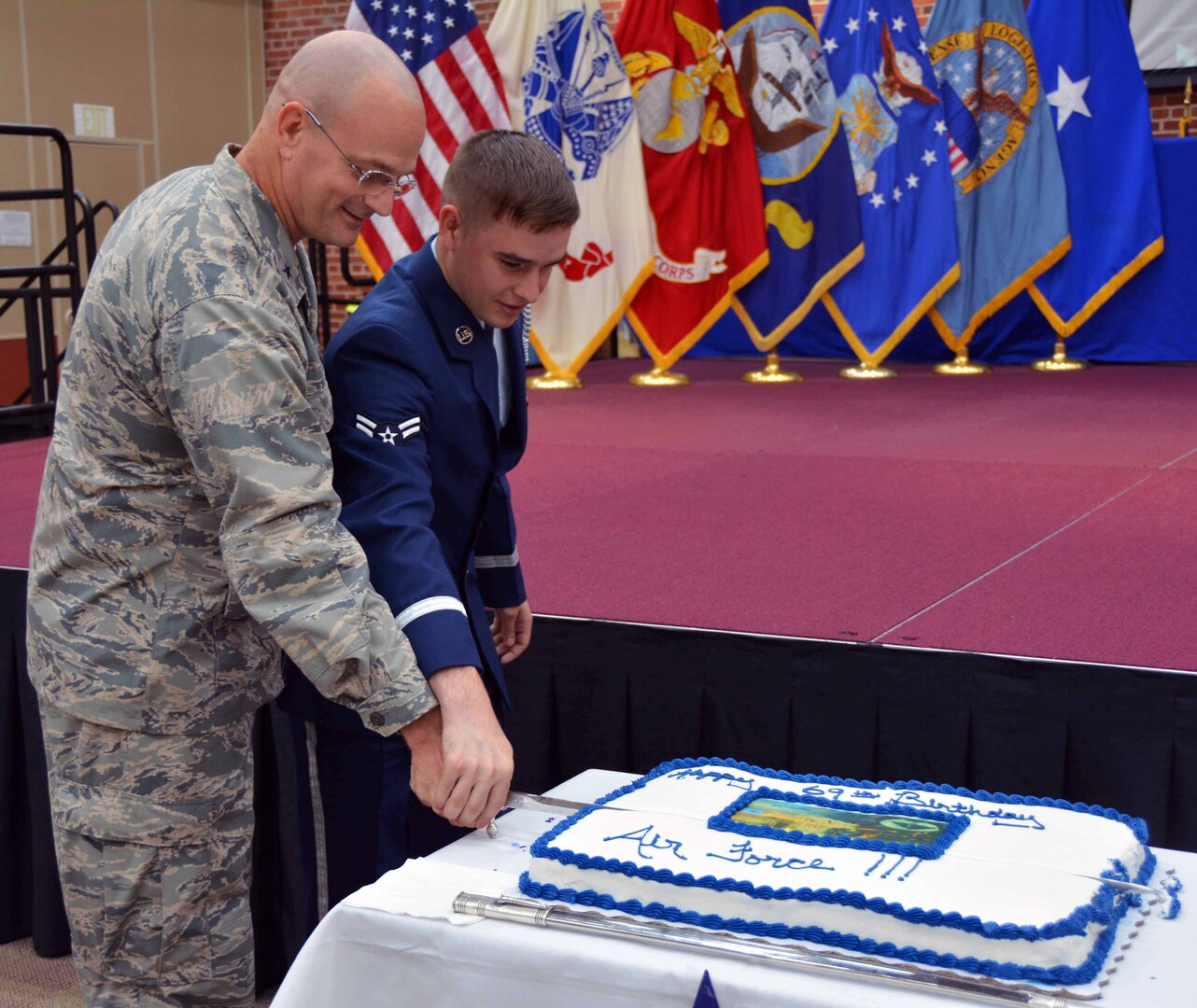Airman 1st Class Ezre Pennington from Langley Air Force Base, Hampton, Virginia, joins Defense Logistics Agency Aviation Commander Air Force Brig. Gen. Allan Day in cutting the cake during the Air Force’s 69th birthday ceremony held at the Lotts Center on Defense Supply Center Richmond, Virginia, Sept. 22, 2016. 