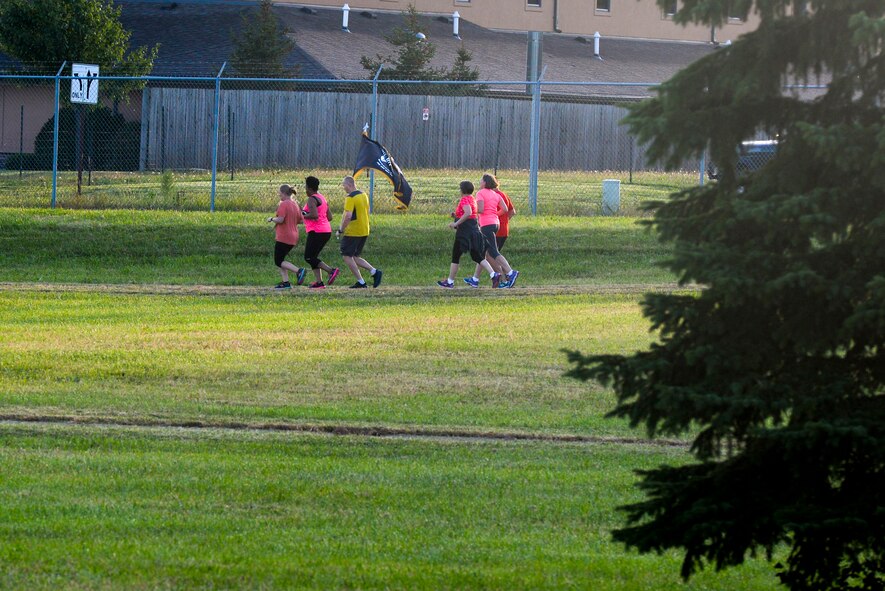 Members of the United States Air Force School of Aerospace Medicine public health office, carry the POW/MIA flag, baton and torch as they run along the Air Force Institute of Technology track lined with POW/MIA and American Flags, during the POW/MIA run at Wright-Patterson Air Force Base, Ohio, Sept. 15, 2016. Runners/Walkers took turns keeping the POW/MIA flag, baton and torch going around the track continuously for 24 hours. (U.S. Air Force photo / Wesley Farnsworth)  