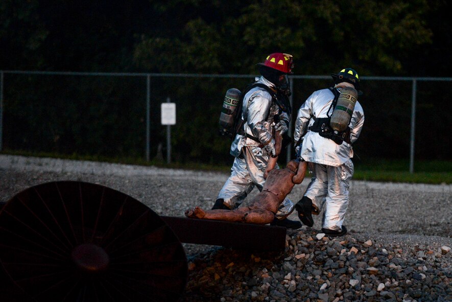 Firefighters from the 788th Civil Engineer Squadron fire department pull a mannequin from an aircraft fuselage after putting out a fire at their training burn pit, Sept. 19, 2016 at Wright-Patterson Air Force Base, Ohio. Crews put out two different kinds of aircraft fires in addition to conducting searches for victims as part of their training. (U.S. Air Force photo by  Wesley Farnsworth)
