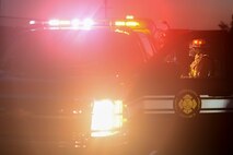 A firefighter with the 788th Civil Engineer Squadron fire department talks with another firefighter at the back of an emergency response vehicle during a fire training call at their training burn pit, Sept. 19, 2016 at Wright-Patterson Air Force Base, Ohio. Crews put out two different kinds of aircraft fires in addition to conducting searches for victims as part of their training. (U.S. Air Force photo by  Wesley Farnsworth)