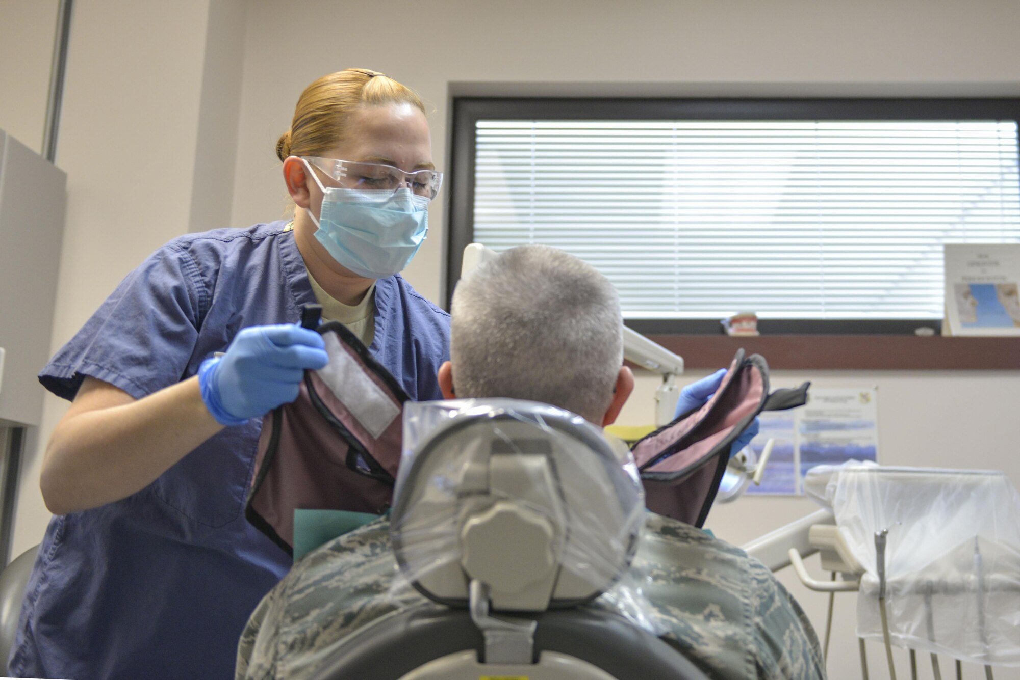 U.S. Air Force Senior Airman Yomarly Rosario Torres, a 354th Medical Operations Support Squadron dental technician, places an X-ray apron on a patient Sept. 23, 2016, at Eielson Air Force Base, Alaska. Dental technicians help with every part of the dental process, from exams to taking X-rays, and even surgery. (U.S. Air Force photo by Airman Isaac Johnson)