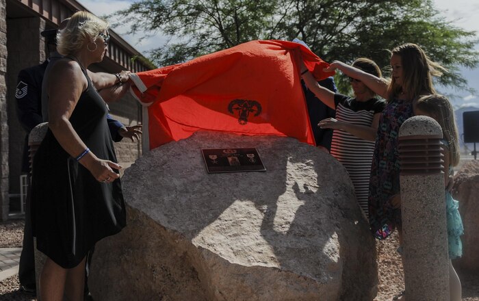 Senior Airman Michael Buras’s family unveils a plaque in his honor during a dedication ceremony of the new explosive ordinance disposal building at Nellis Air Force Base, Nev., Sept. 21. Buras was awarded the Purple Heart in May 2009, while he was a gunner on a mine resistance ambush vehicle. (U.S. Air Force photo by Airman 1st Class Kevin Tanenbaum/Released)