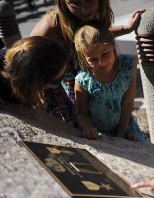 Senior Airman Michael Buras’s daughter Maddison examines the plaque dedicated to her fallen father at the new Explosive Ordinance Disposal building at Nellis Air Force Base, Nev., Sept. 21. On Sept. 21, 2010, in a valiant effort providing cover for fellow Airmen, Senior Airman Michael J. Buras was killed in action by an improvised explosive device while deployed at Operating Location Bravo, Kandahar Airfield, Afghanistan. (U.S. Air Force photo by Airman 1st Class Kevin Tanenbaum/Released)