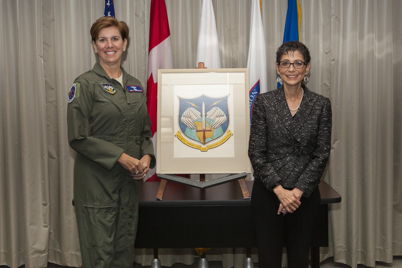 Gen. Lori Robinson, Commander of NORAD and USNORTHCOM, accepts the original NORAD emblem artwork from Ms. Mona Rowe, daughter of the late Mr. Paul Jaffe, designer of the original emblem at the North American Aerospace Defense Command and U.S. Northern Command Headquarters in Colorado Springs, Colo., Sept. 23, 2016.  In honor of her father, Rowe donated his artwork to the commands.  "My father's work resides with family," Rowe said.