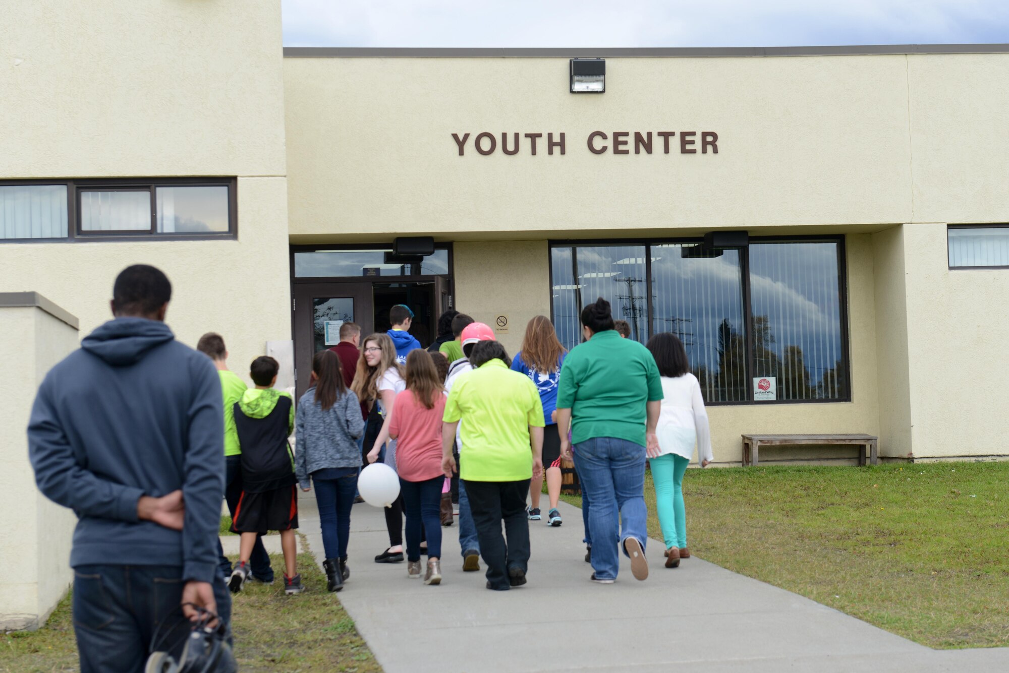 Children, parents and Kennecott Youth Center workers enter the building during the Worldwide Day of Play at Joint Base Elmendorf-Richardson, Alaska, Sept. 21, 2016. The Worldwide Day of Play is an annual event that encourages kids and parents to go outside and play instead of sitting indoors and watching television. Due to inclement weather, the Kennecott Youth Center provided several games and stations like the cupcake walk, indoor rock climbing, batting cage, pitching mound and more.