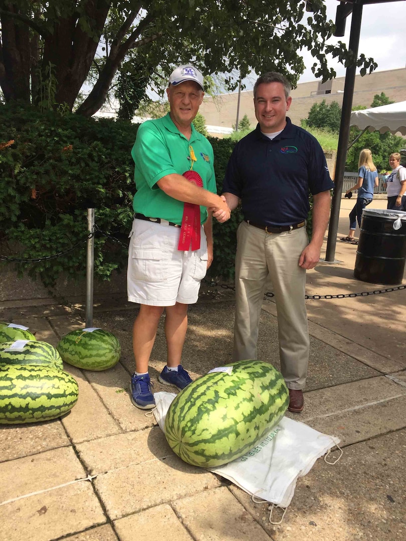 Joe Miller, a Subsistence field rep, stands with the Kentucky Commissioner of Agriculture after his watermelon earned second place at the Kentucky State Fair in August. Miller uses his produce expertise to support DLA Troop Support customers. 