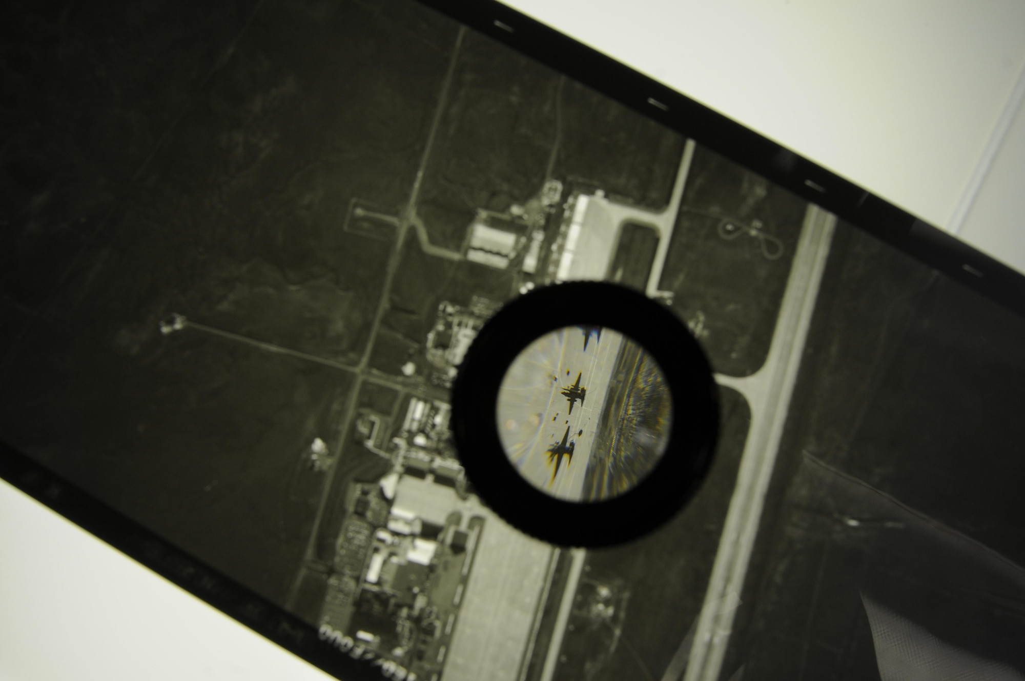 A section of Optical Bar Camera duplicate film is magnified using a loupe, showing two U-2 Dragon Lady aircraft on the Beale Air Force Base flightline. The OBC is carried by the U-2, which routinely flies at an altitude of more than 70,000 feet. (Air Force photo by Airman 1st Class Taylor A. Workman)