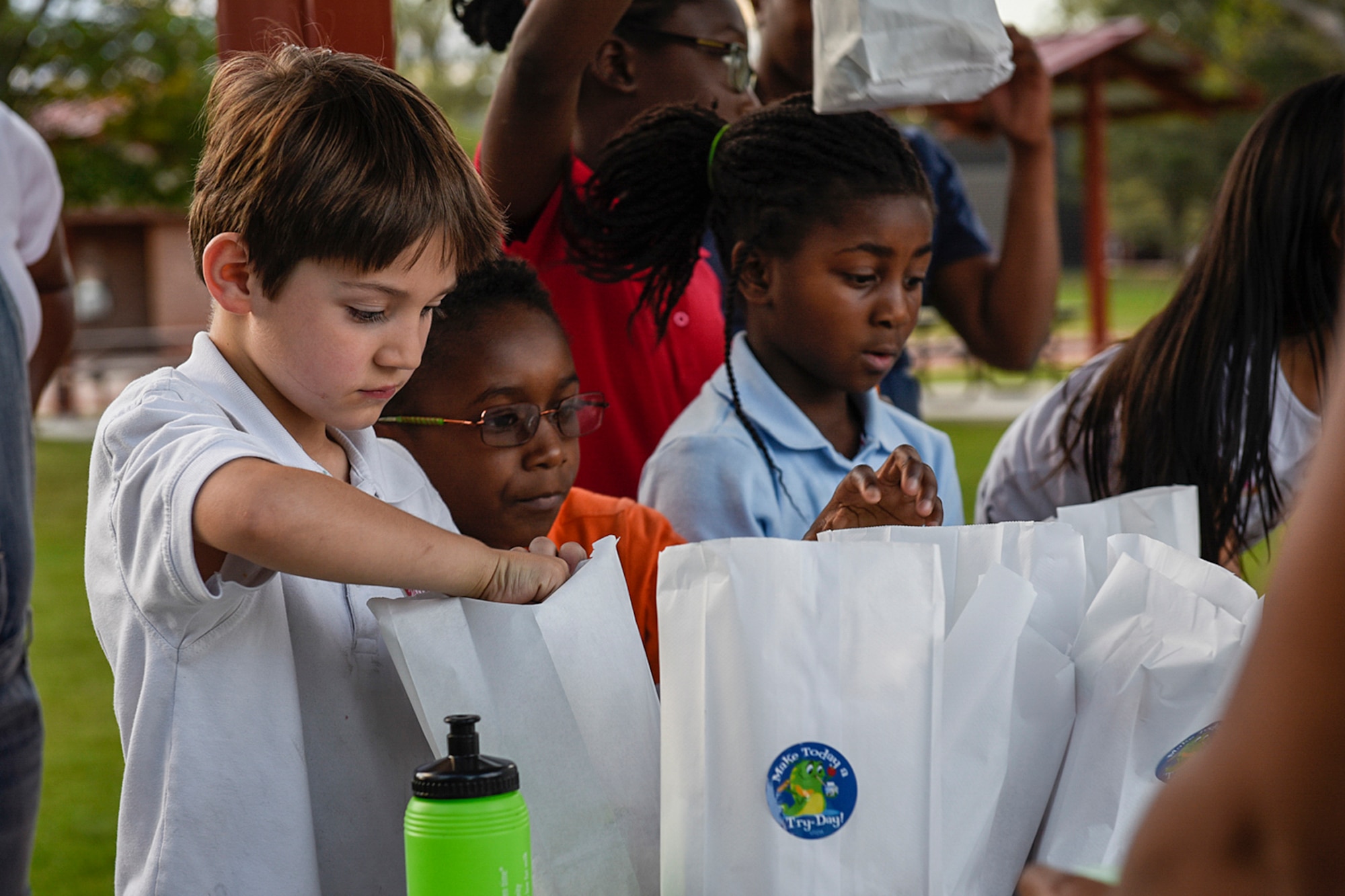 PETERSON AIR FORCE BASE, Colo. – Nick Boughton, left, along with other Peterson youth reach into goodie bags of healthy lunch choices during the Family Fun Night at Lyon’s Park on Peterson Air Force Base, Colo., Sept. 22, 2016. The Health and Wellness Center hosted the event to encourage families to implement healthier activities and snacks into their lifestyles. (U.S. Air Force photo by Senior Airman Rose Gudex)