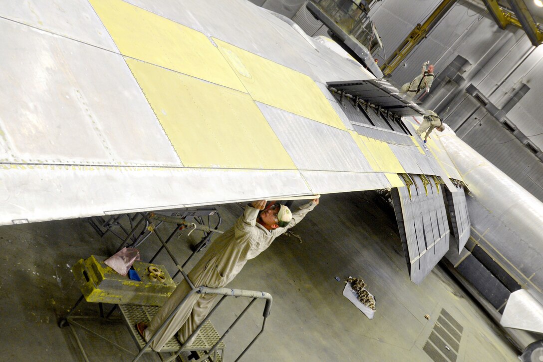 Jake Drew, 566th Aircraft Maintenance Squadron, masks seams on the “Ghost Rider” before the sealant is applied Sept. 19, 2016, at Tinker Air Force Base. Workers in the background are applying the sealant to the historic aircraft before it is painted. (Air Force photo by Kelly White)