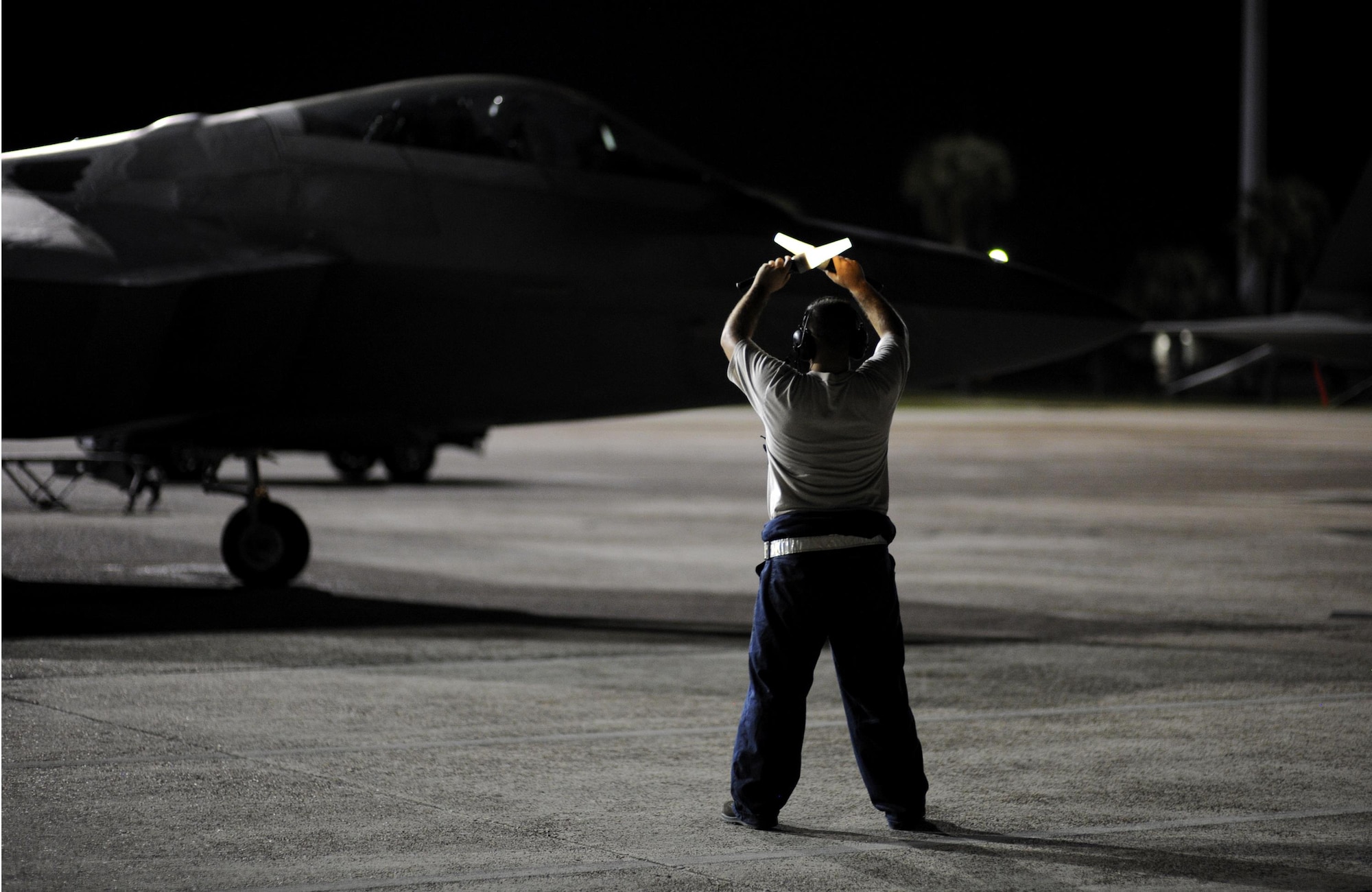 U.S. Air Force Senior Airman Samuel Strickland, 325th Aircraft Maintenance Squadron tactical aircraft maintenance technician, marshals a pilot from the 95th Fighter Squadron as his F-22 Raptor taxis down the Tyndall runway during a night operation Sept. 21, 2016. The 325th AMU, 95th FS, 325th Operations Support Squadron and 325th Security Forces Squadron work together to ensure that the Airmen of Tyndall are trained, prepared and protected while conducting night operations when needed. (U.S. Air Force photo by Senior Airman Solomon Cook/Released) 