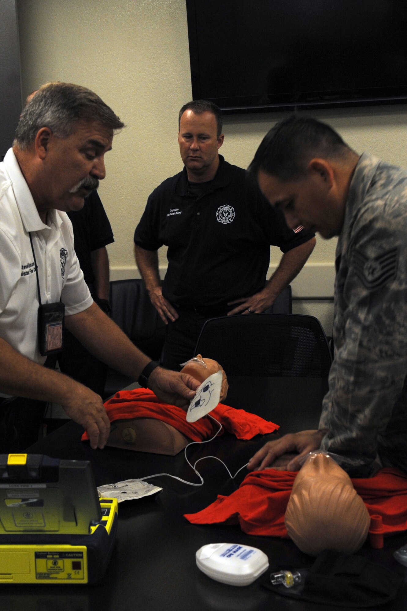 Steven Kinkade, 56th Civil Engineer Squadron assistant fire chief for training, and Tech Sgt. James Hickman, 56th CES fire fighter, demonstrate how to use an automated external defibrillator Sept. 20, 2016, at Luke Air Force Base, Ariz. Proper use of an AED is a core requirement for the CPR recertification class. (U.S. Air Force Photos by Airman 1st Class Pedro Mota)
