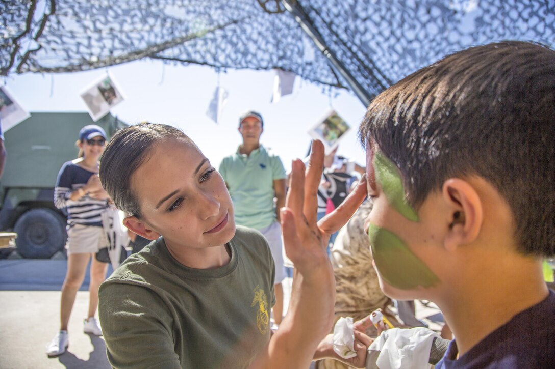 A Marine paints a child's face with camouflage colors during the Miramar Air Show at Marine Corps Air Station Miramar, San Diego, Sept. 24, 2016. The event showcases the aerial expertise of civilian and armed forces. Marine Corps photo by Cpl. Travis Jordan