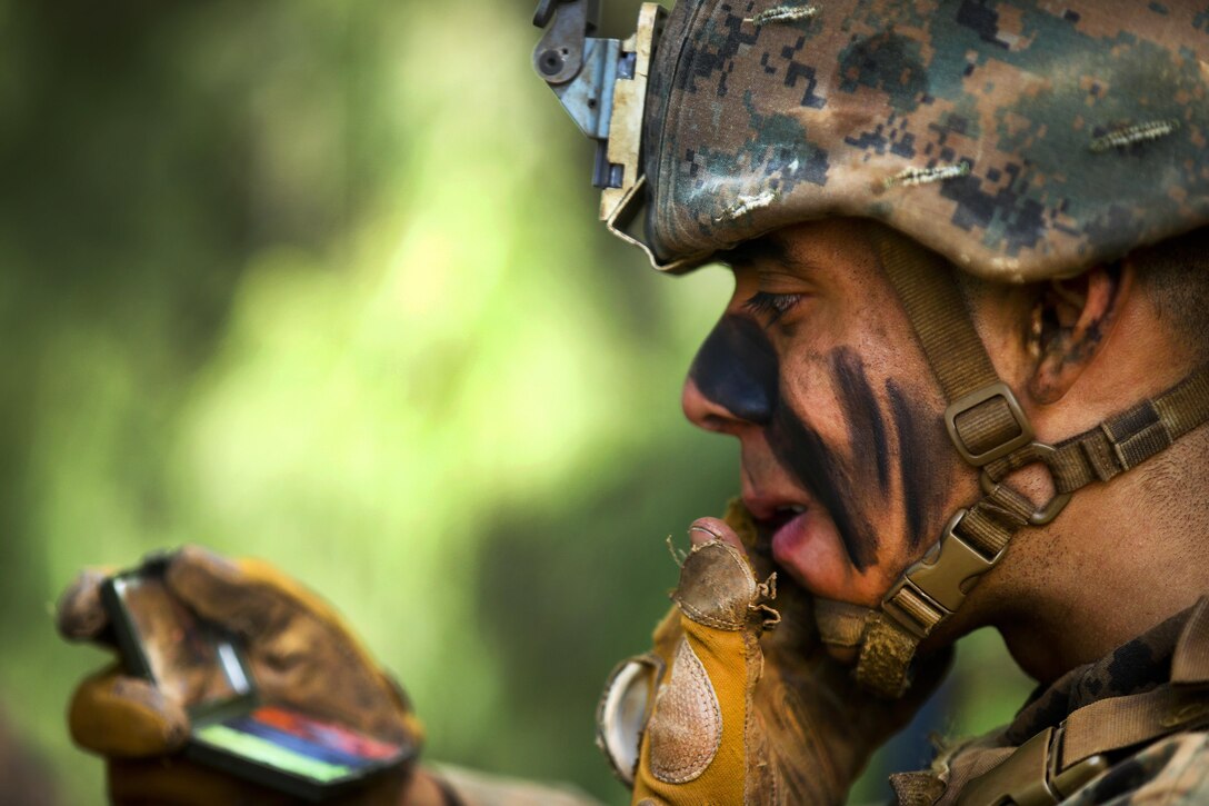 Marine Corps Lance Cpl. Anthony Acedo applies camouflage paint during the advanced infantry course at Kahuku Training Area, Hawaii, Sept. 20, 2016. Acedo is a rifleman assigned to 1st Battalion, 7th Marine Regiment. The course is designed to refine leadership abilities for Marines who serve as squad leaders in a rifle platoon. Marine Corps photo by Cpl. Aaron S. Patterson