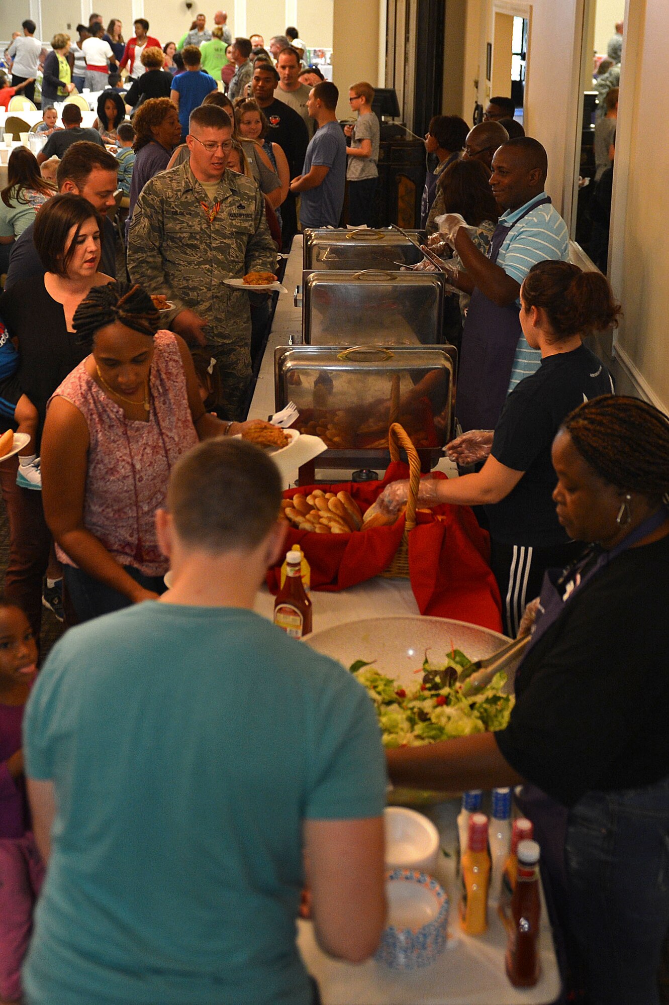 Team Shaw members wait in line for dinner during a deployed family dinner at the Carolina Skies Club and Conference Center at Shaw Air Force Base, S.C, Sept. 26, 2016. The complimentary dinner is held monthly to give back to the families of deployed Airmen by providing food and an outlet to network with others in their current situation. (U.S. Air Force photo by Airman 1st Class Christopher Maldonado)