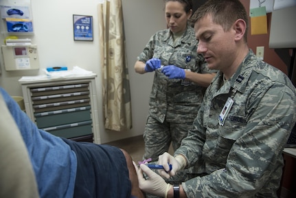 Capt. John Lax (right), 359th Medical Operations Squadron physician, injects medication into a patient’s knee May 2 at the Joint Base San Antonio-Randolph Medical Clinic.

