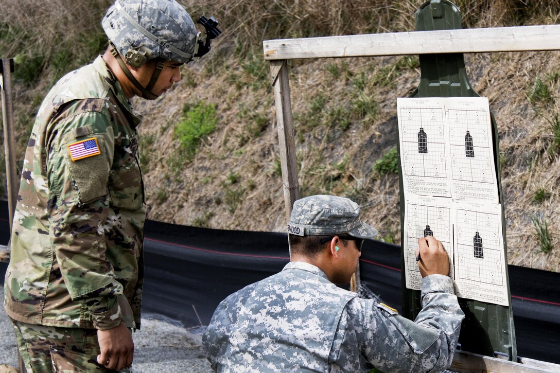 Army Sgt. Julio Redwood, right, grades Army Spc. Ricardo Rodriguez's target after firing with an M4A1 carbine at Camp Smith, N.Y., Sept. 20, 2016. Redwood, a range safety officer, and Rodriguez, a light wheel vehicle mechanic, are assigned to the New York Army National Guard’s 145th Maintenance Battalion. Army National Guard photo by Sgt. Michael Davis