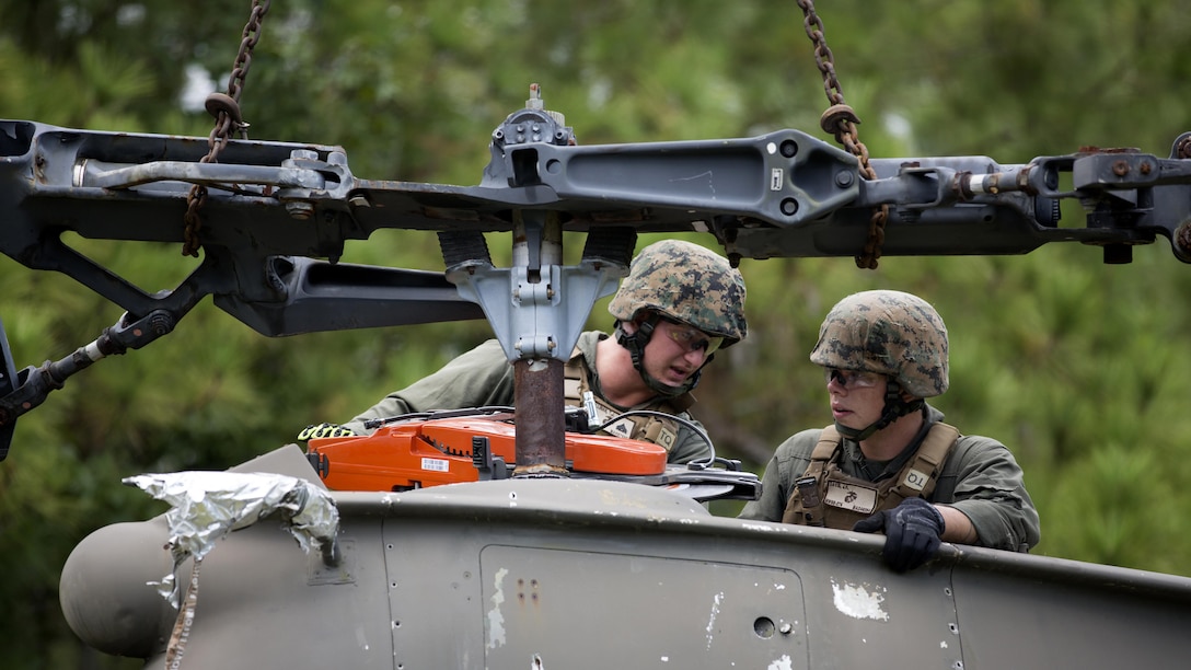 Cpl. Tyler Hallinan (right) demonstrates proper sawing techniques to Lance Cpl. Jacob Davis during a field exercise at Marine Corps Outlying Field Camp Davis, N.C., Sept. 22, 2016. Support squadrons across the Marine Corps often conduct these exercises to remain erady for any challenge they may face in forward deployed environments. This exercise featured events such as auxiliary airfield construction, ground security and airfield damage repair. The squadron's capabilities contribute to 2nd Marine Aircraft Wing's role in the Marine Air Ground Task Force's mission accomplishment. Hallinan and Davis are both aircraft rescue firefighters with Marine Wing Support Squadron 274, Marine Aircraft Group 29, 2nd MAW.