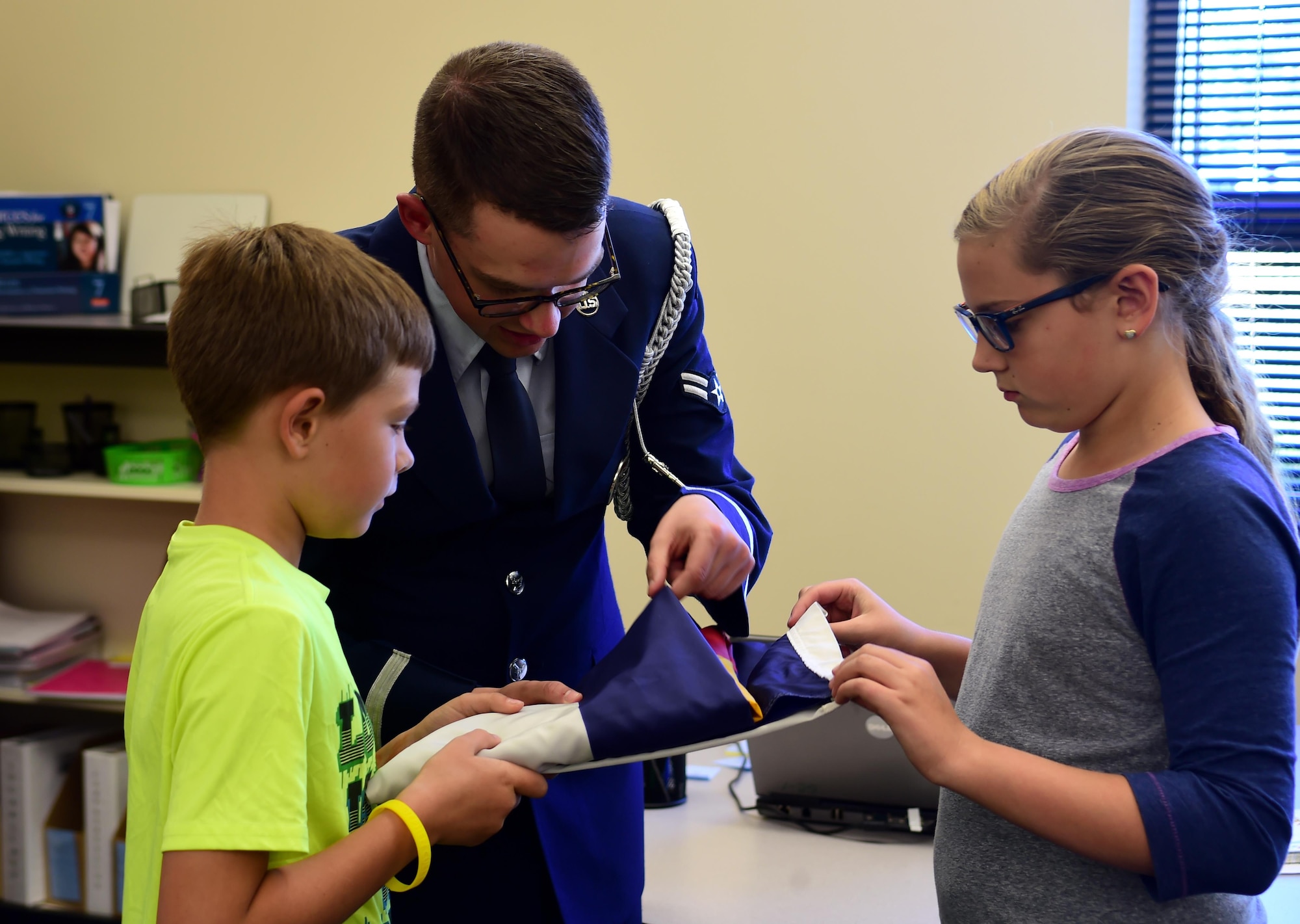 Airman 1st Class Nathan Doty, U.S. Air Force Mile High Honor Guard member, teaches students how to strategically tuck in the excess material of the flag after properly folding it Sep. 27, 2016, at Aurora Frontier P-8 in Aurora, Colo.  Since students at Aurora Frontier P-8 raise and lower the flag each day, faculty and staff invited the Mile High Honor Guard to teach the students proper flag etiquette. (U.S. Air Force photo by Airman Holden S. Faul/ Released)
