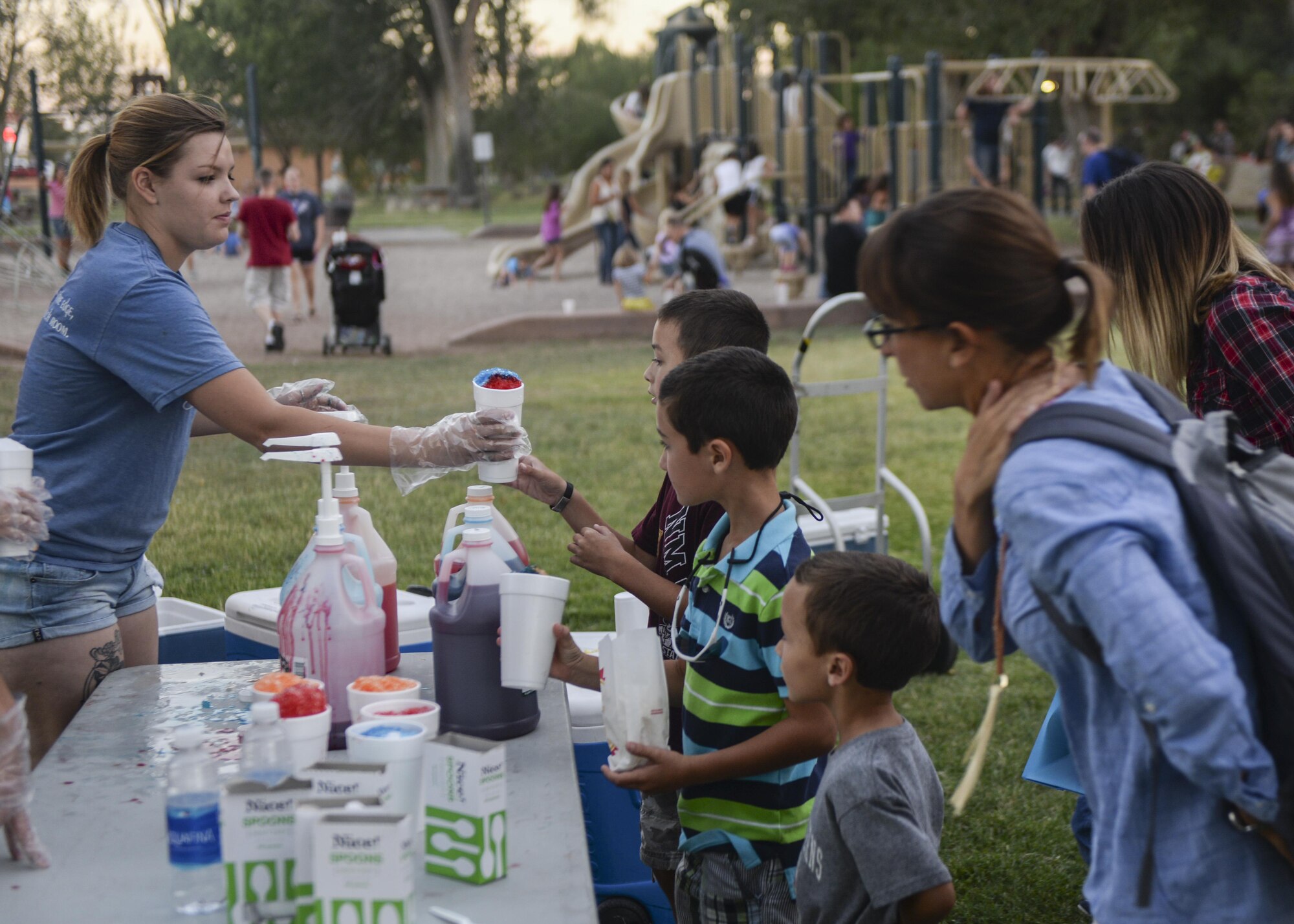 A Holloman volunteer serves a cup of shaved ice at the annual Zoo After Hours event at Alameda Park Zoo in Alamogordo, N.M. on Sept. 24, 2016. Pizza and snack foods, including shaved ice and popcorn, were free to attendees of the event. (U.S. Air Force photo by Airman 1st Class Alexis P. Docherty)