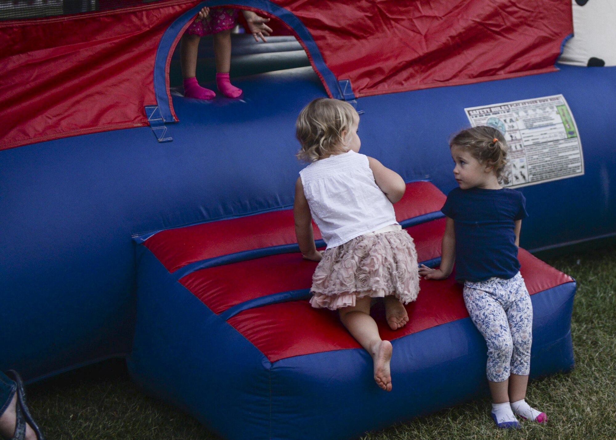 Two young children sit outside a bouncy house during the annual Zoo After Hours event at Alameda Park Zoo in Alamogordo, N.M. on Sept. 24, 2016. The event featured a variety of child-friendly activities including an obstacle course, a bouncy-house and a giant inflatable slide. (U.S. Air Force photo by Airman 1st Class Alexis P. Docherty)