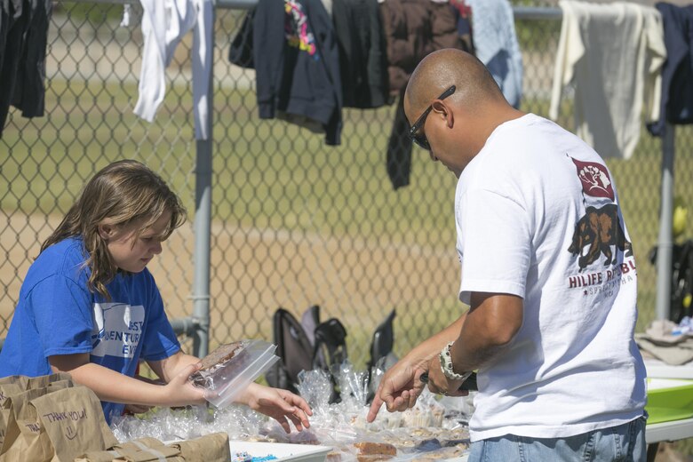 Lacy Tavzel , member, American Red Cross Youth Group, sells baked goods to a Combat Center patron during their Yard and Bake Sale at the Lincoln Military Housing Athletic Field aboard Marine Corps Air Ground Combat Center Twentynine Palms, Calif., Sept. 17, 2016. The event was used as a fund raiser for the youth group and charities. (Official Marine Corps photo by Cpl. Thomas Mudd/Released)