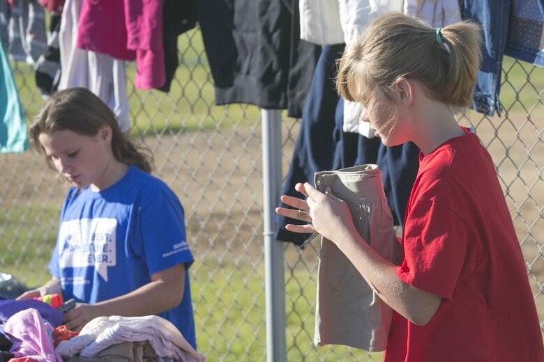 Kassidy Johnson, member, American Red Cross Youth Group, folds cloths while organizing their group’s tables during the Yard and Bake Sale held at the Lincoln Military Housing Athletic Field aboard Marine Corps Air Ground Combat Center Twentynine Palms, Calif., Sept. 17, 2016. The event was used as a fund raiser for the youth group and charities. (Official Marine Corps photo by Cpl. Thomas Mudd/Released)