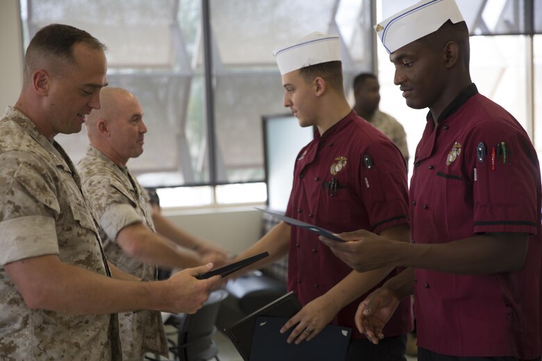 Lance Cpl. Kenneth Martin and Cpl. Darius Henson, food service specialists, Headquarters Battalion, receive certificates after winning people’s choice and chef’s choice during the Chef of the Quarter competition at Phelps Mess Hall aboard Marine Corps Air Ground Combat Center, Twentynine Palms, Calif., Sept. 21, 2016. The competition is held every quarter and provides Marine and civilian chefs aboard the installation an opportunity to showcase their cooking expertise. (Official Marine Corps photo by Cpl. Medina Ayala-Lo/Released)